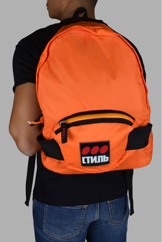 Heron Preston rugzak van oranje stof.Groot vak met rits.Klein vak met rits aan de voorkant.Klein zwart handvat aan de bovenkant.Verstelbare zwarte bandjes.Patch met  Стиль  inscripties op het voorvak.Afmetingen: 33x44x14cm.Gemaakt in Italië.