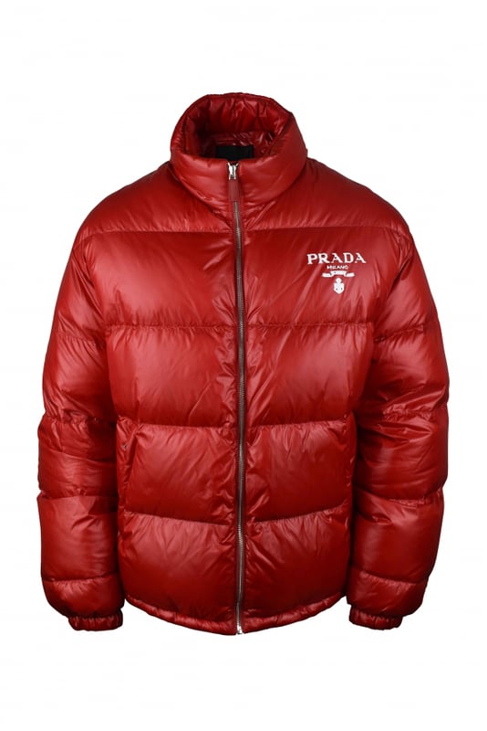 Chaqueta acolchada roja en re-nylon Prada.Logo blanco impreso en el pecho.Cuello alto.Cierre principal con cremallera.Bolsillos laterales con cremallera.