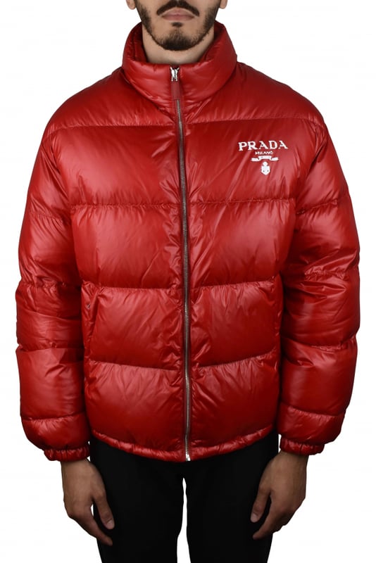 Chaqueta acolchada roja en re-nylon Prada.Logo blanco impreso en el pecho.Cuello alto.Cierre principal con cremallera.Bolsillos laterales con cremallera.
