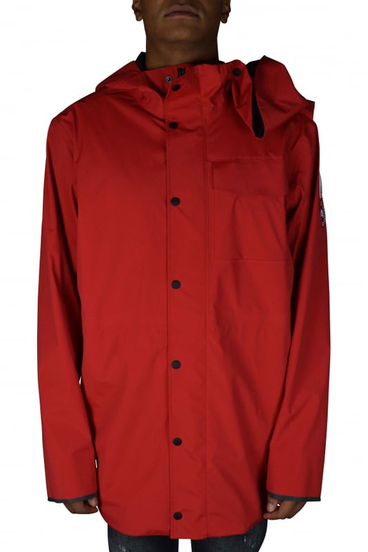 Rote Jacke im Stil von K-Way Y/Project Canada Goose.Stehkragen mit Kapuze.Reißverschluss mit Druckknöpfen.Lange Ärmel.Reflektierende Streifen auf der Rückseite.Aufgenähte Logo-Patches auf dem linken Ärmel.Klettverschlussstreifen zum Verengen an den Ärmeln.Zwei Seitentaschen mit Reißverschluss.Tasche mit Klettverschluss auf der linken Brust.
