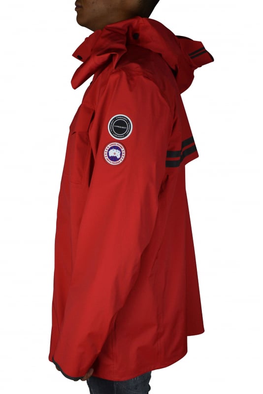 Rote Jacke im Stil von K-Way Y/Project Canada Goose.Stehkragen mit Kapuze.Reißverschluss mit Druckknöpfen.Lange Ärmel.Reflektierende Streifen auf der Rückseite.Aufgenähte Logo-Patches auf dem linken Ärmel.Klettverschlussstreifen zum Verengen an den Ärmeln.Zwei Seitentaschen mit Reißverschluss.Tasche mit Klettverschluss auf der linken Brust.