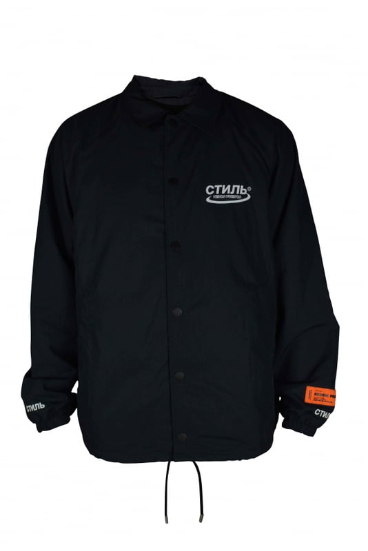 Chaqueta Heron Preston.De color negro.Logotipo impreso en la parte delantera.Cuello con capucha integrada.Parche con logotipo cosido en la manga.Cierre a presión en la parte delantera.Bolsillos laterales.Logotipo en ambos puños cosido en blanco.Parche naranja  HERON PRESTON  en la manga izquierda.Cordón en la cintura.Made in Italy.