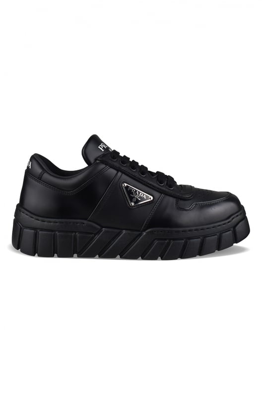 Sneakers de piel negra de Prada.Logotipo triangular de metal esmaltado en el exterior.Parte superior perforada en la parte delantera de la zapatilla.Cierre de cordones negro.Firma Prada blanca en la lengüeta delantera y en el contrafuerte. Suela gruesa de goma.Made in Italy.