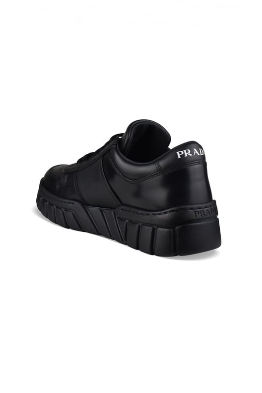 Sneakers de piel negra de Prada.Logotipo triangular de metal esmaltado en el exterior.Parte superior perforada en la parte delantera de la zapatilla.Cierre de cordones negro.Firma Prada blanca en la lengüeta delantera y en el contrafuerte. Suela gruesa de goma.Made in Italy.