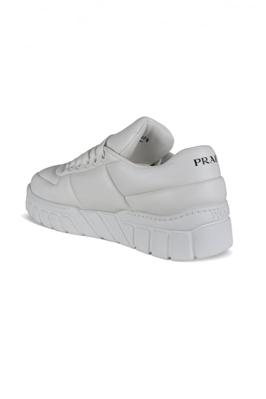 Prada sneakers van wit leer.Gewatteerd leerontwerp.Driehoekig metalen logo aan de buitenkant.Vetersluiting.Prada-handtekening op de tong en aan de voorkant. Dikke rubberen zool.Gemaakt in Italië.