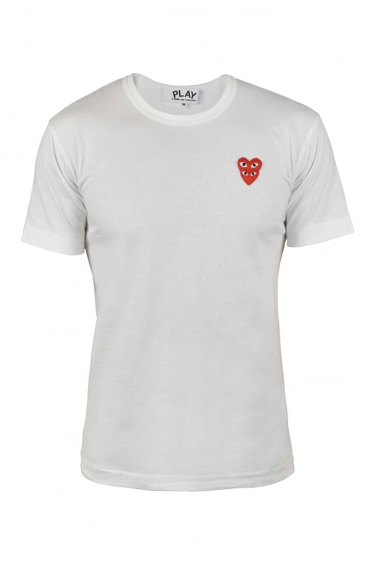Camiseta Comme des Garçons de algodón blanco.Dos parches rojos con el logotipo del corazón bordados y superpuestos en el pecho.Cuello redondo.Mangas cortas.