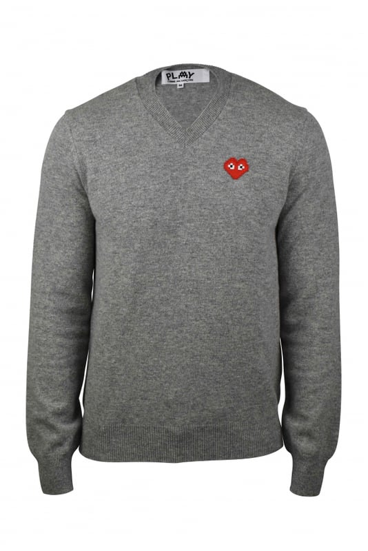 Jersey Comme des Garçons de lana gris con cuello de pico.Corazón rojo emblemático en el pecho.Mangas largas.Bordes de canalé.