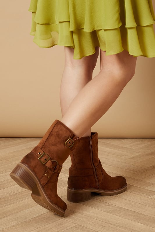 Chunky biker-inspired calf boots
        Faux suede material for a luxe look
        Decorative buckle detailing
        Mid-heel height between 5 and 6.5cm
        Side zip closure for easy on and off
    
    Step out in style with these Lila Faux Suede Chunky Biker Calf Boots from Oasis. These versatile boots blend edgy biker aesthetics with feminine charm, making them perfect for various casual occasions. The mid-heel height offers comfort without sacrificing style, ideal for all-day wear. Pair them with a flowy dress, as seen on our model, for a beautiful contrast between soft and tough elements. These boots are equally at home with skinny jeans and a leather jacket for a more rugged look, or with a midi skirt and cosy jumper for a chic autumn ensemble. Whether you're heading to a family gathering, enjoying a day out shopping, or meeting friends for a casual lunch, these boots will keep you looking fashionable and feeling comfortable.
