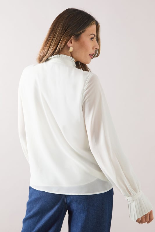 Elegant ruffle neck detail for a sophisticated touch
        Pleated front design adds texture and visual interest
        Long sleeves with gathered cuffs for a refined silhouette
        Versatile woven fabric suitable for various occasions
        Relaxed fit through the body for comfort and ease of movement
    
    This Wallis blouse radiates effortless sophistication with its ruffle neck and pleat detail. Perfect for the woman who appreciates both style and comfort, it's an ideal choice for daywear occasions. Style it with wide-leg trousers and a leather belt for a polished look at family gatherings or casual brunches. The long sleeves with gathered cuffs add a touch of elegance, making it suitable for slightly dressier daytime events. For a more relaxed ensemble, pair it with your favourite jeans and ballet flats. The versatile nature of this blouse allows for easy transition from a day at the office to an evening out with friends. Its timeless design ensures it will remain a staple in your wardrobe for seasons to come, offering endless styling possibilities for the fashion-forward woman who values both glamour and practicality.