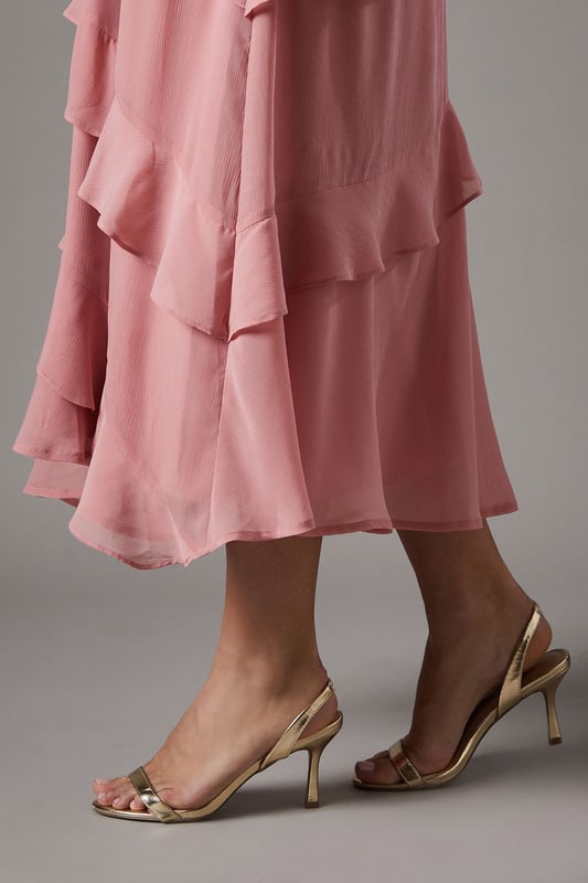Elegant sling back design with delicate barely-there straps for a sophisticated silhouette
        Medium heel height of 5-6.5cm offers the perfect balance of comfort and style
        Sleek metallic finish that catches the light beautifully with every step
        Secure adjustable sling back strap ensures a comfortable, customised fit
        Versatile design that complements both daytime and evening occasion wear
    
    The Vallen Sling Back Sandals from Coast present the quintessential occasion footwear for the discerning woman. These medium-heeled sandals feature a minimalist barely-there design that showcases the foot beautifully whilst providing elegant support. The metallic finish adds a touch of glamour that pairs wonderfully with flowing dresses, as shown with the layered chiffon dress in the imagery. Perfect for weddings, race days and formal gatherings where sophistication is paramount, these sandals will carry you through the day with grace. Style with a structured clutch bag and delicate jewellery for a coordinated ensemble. The modest heel height ensures you can dance the night away or stand comfortably throughout day-long events without compromising on style. These versatile sandals will become a treasured addition to your occasion wardrobe for seasons to come.