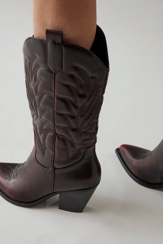 Striking western-inspired calf boots with intricate embroidered detailing
        Brushed faux leather finish for a sophisticated texture
        Pointed toe design with classic pull tabs for easy wear
        Statement 7-9cm block heel adds height whilst maintaining stability
        Calf-height shaft with distinctive western stitching pattern
    
    The Faith Nash Western Boots bring countryside charm to city streets with their distinctive embroidered detailing and brushed finish. The 7-9cm heel creates a flattering silhouette whilst remaining comfortable for all-day wear. Style these versatile boots with a floaty midi dress and oversized jacket for weekend brunches, or pair with straight-leg jeans and a crisp white tee for casual gatherings. For autumn outings, match with a mini skirt and fringed jacket to showcase the boots' western heritage. The pointed toe and sleek silhouette ensure these boots transition effortlessly from day to night, making them a wardrobe essential that combines practicality with statement style. Their classic design promises longevity beyond seasonal trends.