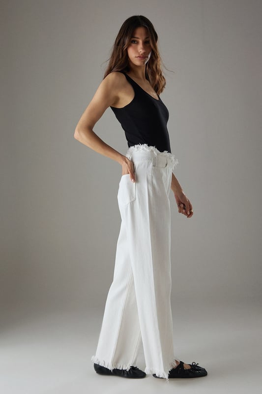 Wide leg silhouette with distinctive fray detailing at waistband and hem for an edgy finish
        Front seam detailing adds architectural interest and elongates the leg
        Cotton fabric provides comfort and breathability for all-day wear
        Practical side and back pockets for everyday functionality
        High-rise waist creates a flattering silhouette that pairs perfectly with cropped tops
    
    These Warehouse wide leg jeans combine contemporary design with effortless wearability. The striking fray detail along the waistband and hem creates a raw, fashion-forward aesthetic that sets these jeans apart from standard denim styles. Style them as shown with a simple fitted vest top for casual daytime outings, or dress them up with a tucked-in blouse and statement jewellery for lunch with friends. The cotton fabric ensures these jeans move comfortably with you throughout the day, while the front seam detailing creates a leg-lengthening effect. Perfect for weekend brunches, gallery visits or casual shopping trips, these jeans offer versatility without compromising on style. Complete the look with flat loafers or trainers for an understated daytime ensemble, or add a structured jacket for a more polished finish.