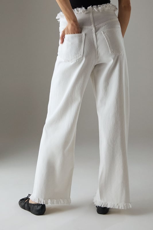 Wide leg silhouette with distinctive fray detailing at waistband and hem for an edgy finish
        Front seam detailing adds architectural interest and elongates the leg
        Cotton fabric provides comfort and breathability for all-day wear
        Practical side and back pockets for everyday functionality
        High-rise waist creates a flattering silhouette that pairs perfectly with cropped tops
    
    These Warehouse wide leg jeans combine contemporary design with effortless wearability. The striking fray detail along the waistband and hem creates a raw, fashion-forward aesthetic that sets these jeans apart from standard denim styles. Style them as shown with a simple fitted vest top for casual daytime outings, or dress them up with a tucked-in blouse and statement jewellery for lunch with friends. The cotton fabric ensures these jeans move comfortably with you throughout the day, while the front seam detailing creates a leg-lengthening effect. Perfect for weekend brunches, gallery visits or casual shopping trips, these jeans offer versatility without compromising on style. Complete the look with flat loafers or trainers for an understated daytime ensemble, or add a structured jacket for a more polished finish.