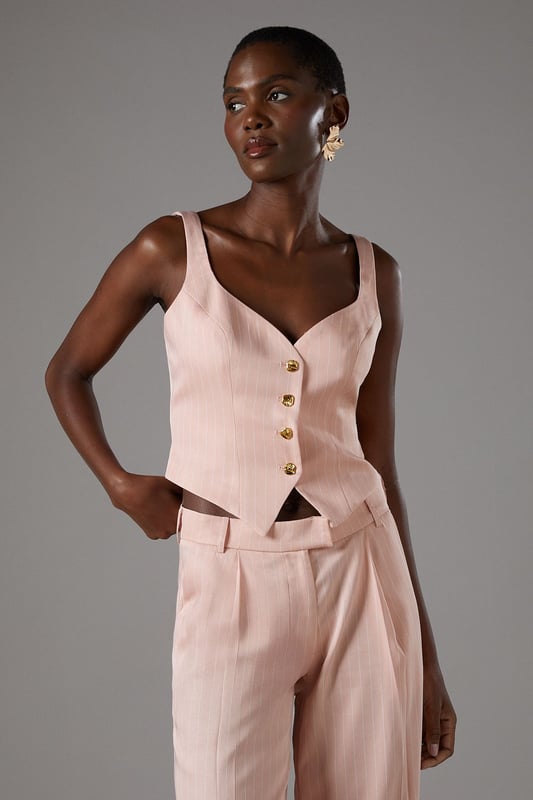 Elegant pinstripe crepe waistcoat with flattering V-neckline
        Strappy design with wide shoulder straps for comfortable wear
        Decorative gold-tone button fastening down the front
        Tailored fit with a slightly cropped silhouette
        Versatile separate that can be styled as part of a coordinating set
    
    This sophisticated Coast waistcoat offers a contemporary twist on traditional tailoring. The strappy design and V-neckline create a feminine silhouette whilst maintaining a structured, polished appearance. Style as seen with the matching wide-leg trousers for a refined coordinating ensemble perfect for summer occasions. For race day elegance, pair with a fascinator and statement earrings, or dress down for garden parties with delicate sandals and a clutch bag. The versatile piece transitions beautifully from day to evening events-simply add a tailored blazer for cooler evenings. The structured crepe fabric holds its shape beautifully whilst offering comfort throughout your special occasion. A timeless investment piece that will become a cornerstone of your occasion wardrobe for seasons to come.