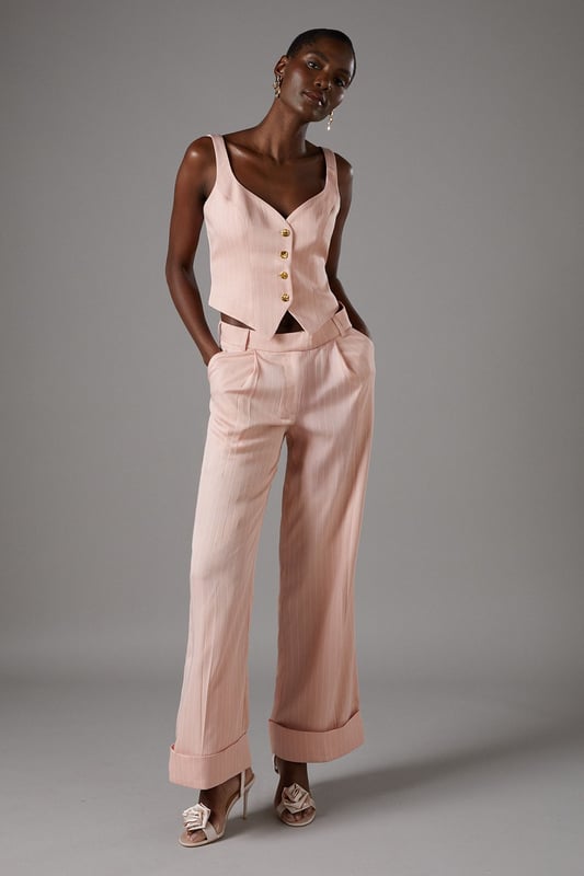 Elegant pinstripe crepe waistcoat with flattering V-neckline
        Strappy design with wide shoulder straps for comfortable wear
        Decorative gold-tone button fastening down the front
        Tailored fit with a slightly cropped silhouette
        Versatile separate that can be styled as part of a coordinating set
    
    This sophisticated Coast waistcoat offers a contemporary twist on traditional tailoring. The strappy design and V-neckline create a feminine silhouette whilst maintaining a structured, polished appearance. Style as seen with the matching wide-leg trousers for a refined coordinating ensemble perfect for summer occasions. For race day elegance, pair with a fascinator and statement earrings, or dress down for garden parties with delicate sandals and a clutch bag. The versatile piece transitions beautifully from day to evening events-simply add a tailored blazer for cooler evenings. The structured crepe fabric holds its shape beautifully whilst offering comfort throughout your special occasion. A timeless investment piece that will become a cornerstone of your occasion wardrobe for seasons to come.