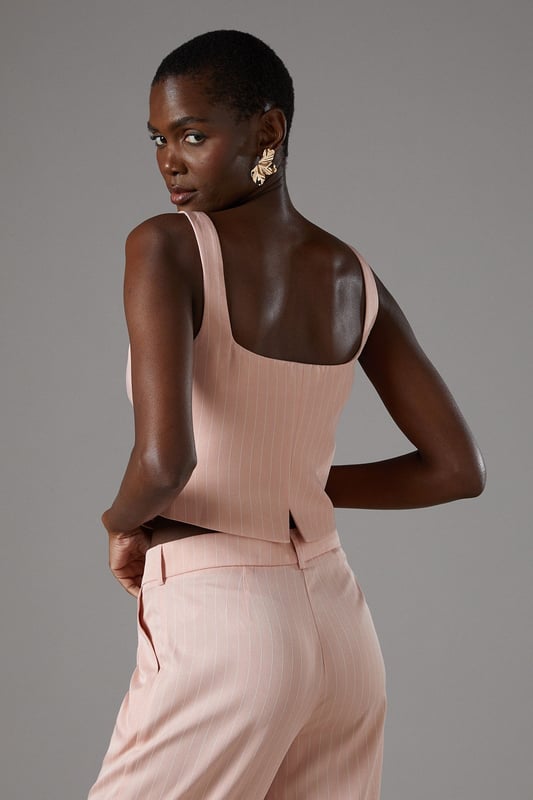 Elegant pinstripe crepe waistcoat with flattering V-neckline
        Strappy design with wide shoulder straps for comfortable wear
        Decorative gold-tone button fastening down the front
        Tailored fit with a slightly cropped silhouette
        Versatile separate that can be styled as part of a coordinating set
    
    This sophisticated Coast waistcoat offers a contemporary twist on traditional tailoring. The strappy design and V-neckline create a feminine silhouette whilst maintaining a structured, polished appearance. Style as seen with the matching wide-leg trousers for a refined coordinating ensemble perfect for summer occasions. For race day elegance, pair with a fascinator and statement earrings, or dress down for garden parties with delicate sandals and a clutch bag. The versatile piece transitions beautifully from day to evening events-simply add a tailored blazer for cooler evenings. The structured crepe fabric holds its shape beautifully whilst offering comfort throughout your special occasion. A timeless investment piece that will become a cornerstone of your occasion wardrobe for seasons to come.