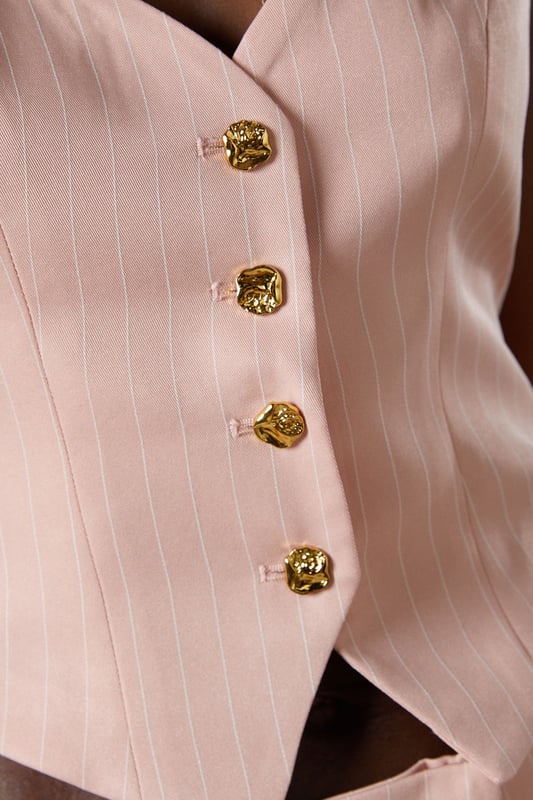 Elegant pinstripe crepe waistcoat with flattering V-neckline
        Strappy design with wide shoulder straps for comfortable wear
        Decorative gold-tone button fastening down the front
        Tailored fit with a slightly cropped silhouette
        Versatile separate that can be styled as part of a coordinating set
    
    This sophisticated Coast waistcoat offers a contemporary twist on traditional tailoring. The strappy design and V-neckline create a feminine silhouette whilst maintaining a structured, polished appearance. Style as seen with the matching wide-leg trousers for a refined coordinating ensemble perfect for summer occasions. For race day elegance, pair with a fascinator and statement earrings, or dress down for garden parties with delicate sandals and a clutch bag. The versatile piece transitions beautifully from day to evening events-simply add a tailored blazer for cooler evenings. The structured crepe fabric holds its shape beautifully whilst offering comfort throughout your special occasion. A timeless investment piece that will become a cornerstone of your occasion wardrobe for seasons to come.