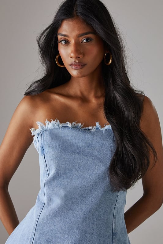 Strapless bandeau design with distinctive frayed edge detailing along the top and bottom hems
        Structured cotton denim fabric provides excellent shape retention and support
        Flattering A-line silhouette that gently flares from the bust to create a feminine profile
        Versatile length that works perfectly as a standalone top or layered piece
        Visible seam detailing adds architectural interest and enhances the contemporary aesthetic
    
    This Warehouse denim bandeau top brings effortless edge to your daywear collection. The raw, frayed edges create a deliberately undone finish that contrasts beautifully with the structured silhouette. Style with the matching frayed denim trousers for a coordinated set that makes a statement, or break it up with your favourite high-waisted jeans for a double denim moment. For casual outings, pair with trainers and oversized gold hoops for an ensemble that transitions seamlessly from weekend brunches to afternoon shopping trips. The cotton fabric offers breathable comfort whilst maintaining its shape throughout the day. This piece embodies Warehouse's confident, feminine aesthetic - perfect for the fashion-forward woman who appreciates contemporary design with a touch of attitude.