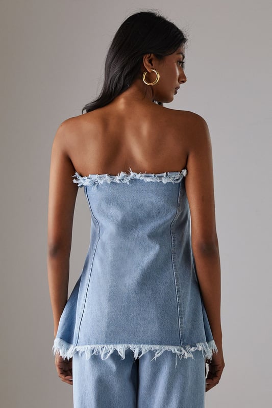 Strapless bandeau design with distinctive frayed edge detailing along the top and bottom hems
        Structured cotton denim fabric provides excellent shape retention and support
        Flattering A-line silhouette that gently flares from the bust to create a feminine profile
        Versatile length that works perfectly as a standalone top or layered piece
        Visible seam detailing adds architectural interest and enhances the contemporary aesthetic
    
    This Warehouse denim bandeau top brings effortless edge to your daywear collection. The raw, frayed edges create a deliberately undone finish that contrasts beautifully with the structured silhouette. Style with the matching frayed denim trousers for a coordinated set that makes a statement, or break it up with your favourite high-waisted jeans for a double denim moment. For casual outings, pair with trainers and oversized gold hoops for an ensemble that transitions seamlessly from weekend brunches to afternoon shopping trips. The cotton fabric offers breathable comfort whilst maintaining its shape throughout the day. This piece embodies Warehouse's confident, feminine aesthetic - perfect for the fashion-forward woman who appreciates contemporary design with a touch of attitude.
