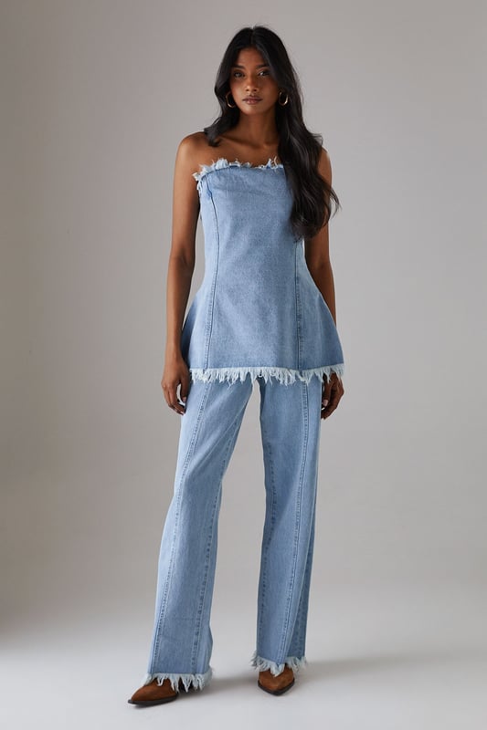 Strapless bandeau design with distinctive frayed edge detailing along the top and bottom hems
        Structured cotton denim fabric provides excellent shape retention and support
        Flattering A-line silhouette that gently flares from the bust to create a feminine profile
        Versatile length that works perfectly as a standalone top or layered piece
        Visible seam detailing adds architectural interest and enhances the contemporary aesthetic
    
    This Warehouse denim bandeau top brings effortless edge to your daywear collection. The raw, frayed edges create a deliberately undone finish that contrasts beautifully with the structured silhouette. Style with the matching frayed denim trousers for a coordinated set that makes a statement, or break it up with your favourite high-waisted jeans for a double denim moment. For casual outings, pair with trainers and oversized gold hoops for an ensemble that transitions seamlessly from weekend brunches to afternoon shopping trips. The cotton fabric offers breathable comfort whilst maintaining its shape throughout the day. This piece embodies Warehouse's confident, feminine aesthetic - perfect for the fashion-forward woman who appreciates contemporary design with a touch of attitude.