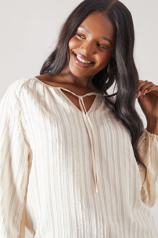 Elegant striped woven top with delicate embroidery detail throughout
        Feminine tie-front closure with keyhole neckline for a sophisticated touch
        Flattering gathered neckline creating a soft, flowing silhouette
        Voluminous balloon sleeves with elasticated cuffs for comfort and style
        Relaxed fit design with a curved hem for versatile styling options
    
    This charming Wallis top combines comfort with effortless sophistication. The gathered neckline and balloon sleeves create a flattering silhouette that works beautifully for daytime occasions. Style with wide-leg denim trousers and sandals, as shown, for family lunches or casual gatherings. The embroidered stripe pattern adds texture and interest, making this piece stand out from basic tops in your collection. For cooler days, layer under a lightweight cardigan or denim jacket. The tie-front detail allows you to adjust the neckline to your preference, while the relaxed fit ensures all-day comfort without compromising on style. Perfect for weekend brunches, shopping trips or casual meet-ups with friends when you want to look polished yet feel comfortable.