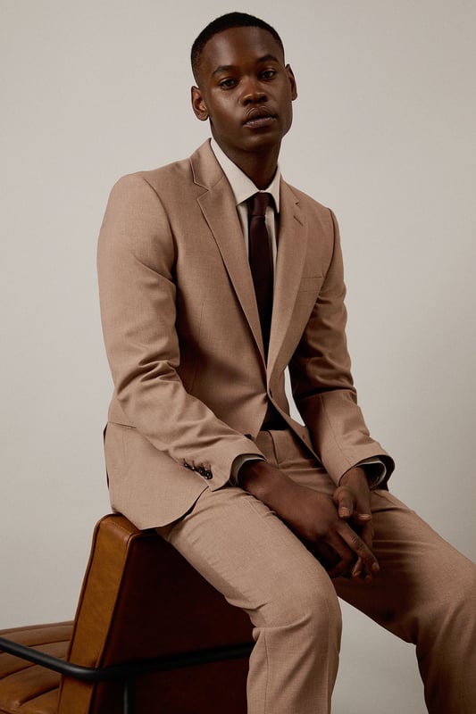 Textured woven fabric adds subtle depth and visual interest to this slim fit jacket
        Notched lapels and two-button fastening create a classic silhouette
        Flap pockets provide practical storage whilst maintaining clean lines
        Slim fit design contours to the body for a modern, defined shape
        Single back vent ensures ease of movement and maintains the jacket's tailored appearance
    
    This Burton suit jacket combines timeless design with contemporary tailoring for the modern gentleman. The slim fit is cut to define your shoulders and chest while tapering at the waist for a sharp silhouette that's both flattering and comfortable. Style with the matching trousers as shown, paired with a crisp white shirt and burgundy tie for formal occasions or business meetings. For smart casual events, dress down with a quality knit and dark jeans. The versatile hue works brilliantly year-round and transitions seamlessly from daytime meetings to evening gatherings. Perfect for those who appreciate classic style with a refined edge, this jacket will become a cornerstone of your smart wardrobe, ideal for everything from important presentations to sophisticated social events at the local pub.