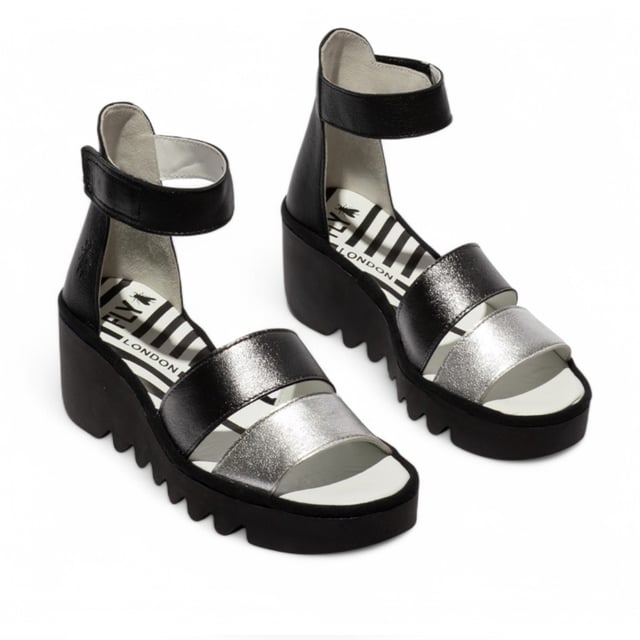 Luce estilo y comodidad con las sandalias BONO290FLY de la línea BLU de Fly London. Diseñadas para un uso cómodo, estas sandalias de cuña cuentan con una elegante parte superior de cuero, plantilla acolchada y una correa de tobillo segura para una sujeción óptima durante todo el día. Características principales: Parte superior de cuero de primera calidad: suave, duradera y elegante. Forro y plantilla de cuero: garantizan comodidad y transpirabilidad. Correa de tobillo ajustable con velcro: fácil de usar y con ajuste personalizado. Plantilla acolchada: proporciona sujeción y comodidad duraderas. Suela de cuña de goma TR resistente: mejora el agarre y la estabilidad. Tacón de cuña de 6,5 cm: aumenta la altura sin comprometer la comodidad.