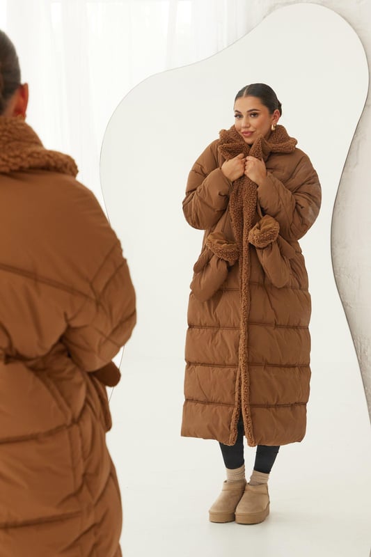 Longline quilted coat with cosy teddy lining for ultimate warmth
        Oversized fit with dropped shoulders for a relaxed silhouette
        High collar and full-length sleeves for maximum coverage
        Matching teddy gloves included for a coordinated winter look
        Versatile design suitable for various casual outings
    
    Embrace the chilly season in style with this statement longline coat from Boohoo. The quilted outer layer combined with the plush teddy lining offers unparalleled warmth without compromising on fashion. Perfect for those who want to make a bold impression while staying snug, this coat is ideal for casual winter outings, from coffee runs to weekend markets. Style it as seen on the model with slim-fit trousers and comfy trainers for an effortlessly chic ensemble. The included teddy gloves add an extra touch of cosiness and coordination to your look. Whether you're walking the dog or meeting friends for a casual brunch, this coat will keep you looking fabulous and feeling toasty. Its oversized fit allows for easy layering over chunky knits, making it a versatile piece for your cold-weather wardrobe.