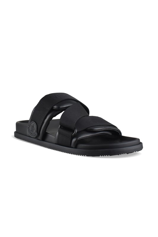 Mon Summer-slipper van zwart Moncler-leer.Gekruiste bandjes van polyester met logo.Klittenbandsluitingen.Logopatch aan de buitenkant.Platte zool.Made in Italy.