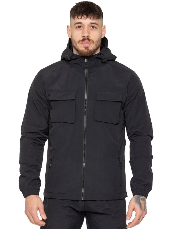 The Enzo Milano Men’s Lightweight Cargo Jacket is a sleek, functional outer layer made from water-repellent crushed poly fabric with a breathable mesh lining for all-day comfort. Designed in a regular fit, it features a full zip front, high neck, and adjustable drawcord hood for versatile coverage. With two Velcro chest pockets, two zippered side pockets, elasticated cuffs, and an adjustable drawcord hem, it offers both style and practicality—perfect for layering in changing weather.