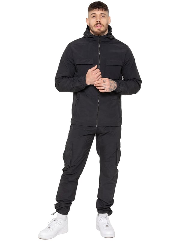 The Enzo Milano Men’s Lightweight Cargo Jacket is a sleek, functional outer layer made from water-repellent crushed poly fabric with a breathable mesh lining for all-day comfort. Designed in a regular fit, it features a full zip front, high neck, and adjustable drawcord hood for versatile coverage. With two Velcro chest pockets, two zippered side pockets, elasticated cuffs, and an adjustable drawcord hem, it offers both style and practicality—perfect for layering in changing weather.
