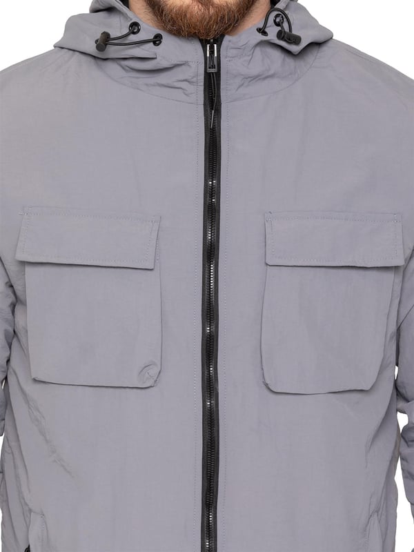 The Enzo Milano Men’s Lightweight Cargo Jacket is a sleek, functional outer layer made from water-repellent crushed poly fabric with a breathable mesh lining for all-day comfort. Designed in a regular fit, it features a full zip front, high neck, and adjustable drawcord hood for versatile coverage. With two Velcro chest pockets, two zippered side pockets, elasticated cuffs, and an adjustable drawcord hem, it offers both style and practicality—perfect for layering in changing weather.