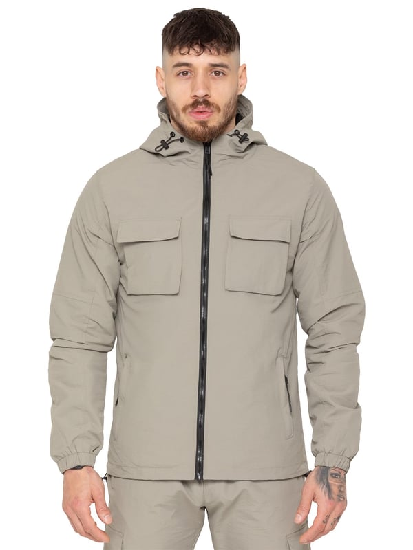 The Enzo Milano Men’s Lightweight Cargo Jacket is a sleek, functional outer layer made from water-repellent crushed poly fabric with a breathable mesh lining for all-day comfort. Designed in a regular fit, it features a full zip front, high neck, and adjustable drawcord hood for versatile coverage. With two Velcro chest pockets, two zippered side pockets, elasticated cuffs, and an adjustable drawcord hem, it offers both style and practicality—perfect for layering in changing weather.