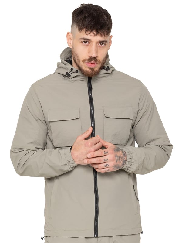 The Enzo Milano Men’s Lightweight Cargo Jacket is a sleek, functional outer layer made from water-repellent crushed poly fabric with a breathable mesh lining for all-day comfort. Designed in a regular fit, it features a full zip front, high neck, and adjustable drawcord hood for versatile coverage. With two Velcro chest pockets, two zippered side pockets, elasticated cuffs, and an adjustable drawcord hem, it offers both style and practicality—perfect for layering in changing weather.