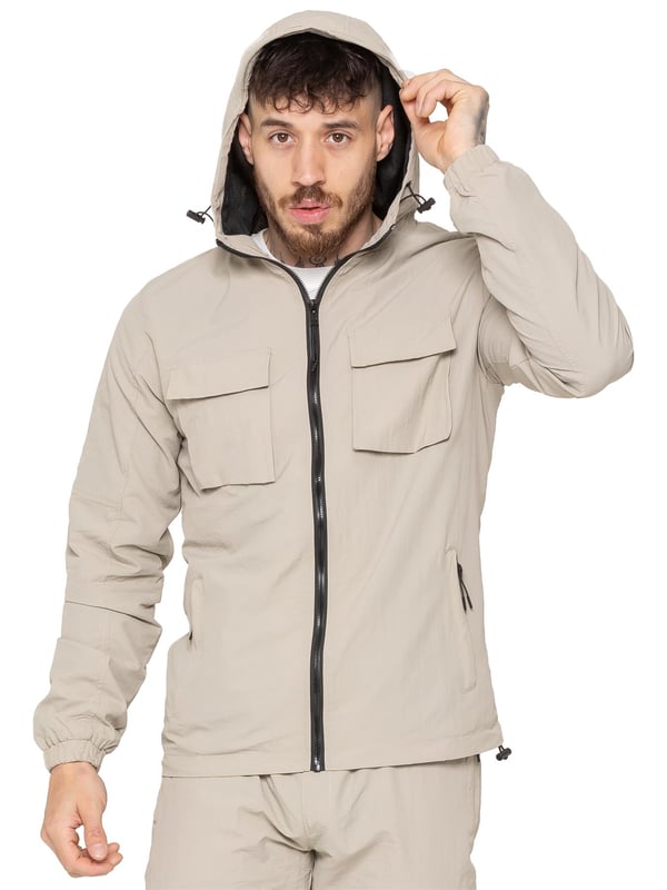 The Enzo Milano Men’s Lightweight Cargo Jacket is a sleek, functional outer layer made from water-repellent crushed poly fabric with a breathable mesh lining for all-day comfort. Designed in a regular fit, it features a full zip front, high neck, and adjustable drawcord hood for versatile coverage. With two Velcro chest pockets, two zippered side pockets, elasticated cuffs, and an adjustable drawcord hem, it offers both style and practicality—perfect for layering in changing weather.