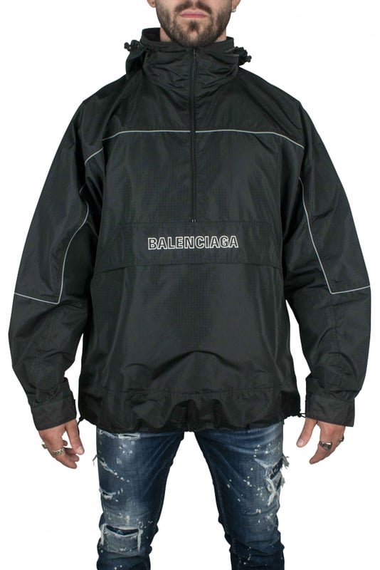 Chaqueta negra de poliéster impermeable de Balenciaga.Logotipo blanco en el centro.Logotipo blanco en la espalda.Línea fluorescente.Cuello alto con cremallera.Capucha desmontable.Bolsillo canguro.Mangas largas.Cordones en el bajo.Made in Italy.