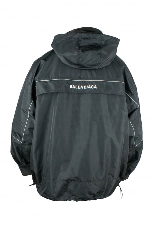 Chaqueta negra de poliéster impermeable de Balenciaga.Logotipo blanco en el centro.Logotipo blanco en la espalda.Línea fluorescente.Cuello alto con cremallera.Capucha desmontable.Bolsillo canguro.Mangas largas.Cordones en el bajo.Made in Italy.