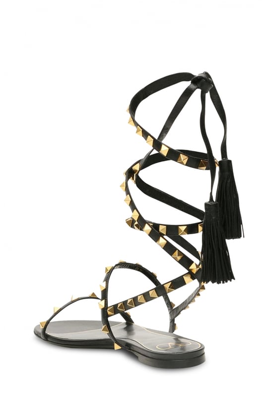 Sandalias Valentino Garavani en piel color negro.Tirantes de piel con tachuelas doradas y borlas de piel.Suela con tacón plano.Made in Italy.