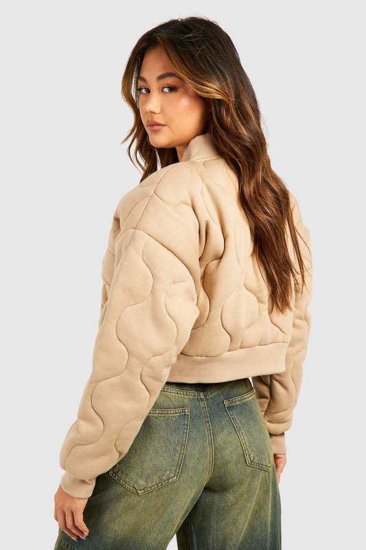 Quilted design for added texture and warmth
        Cropped length for a trendy silhouette
        Ribbed collar and cuffs for a snug fit
        Front zip closure for easy wear
        Functional front pockets for practicality
    
    This gesteppte Bomberjacke from Boohoo is the perfect blend of style and comfort for the fashion-forward woman. The quilted design not only adds visual interest but also provides extra warmth for those chilly days. Its cropped length is ideal for showcasing high-waisted trousers or skirts, creating a balanced and modern look. Style it with wide-leg jeans and trainers for a casual day out, or dress it up with a midi skirt and ankle boots for a night on the town. The versatile nature of this jacket makes it a go-to piece for various occasions, from casual meetups with friends to laid-back family gatherings. Its timeless appeal ensures it will remain a staple in your wardrobe for seasons to come, easily adaptable to the latest trends while maintaining its classic bomber jacket charm.