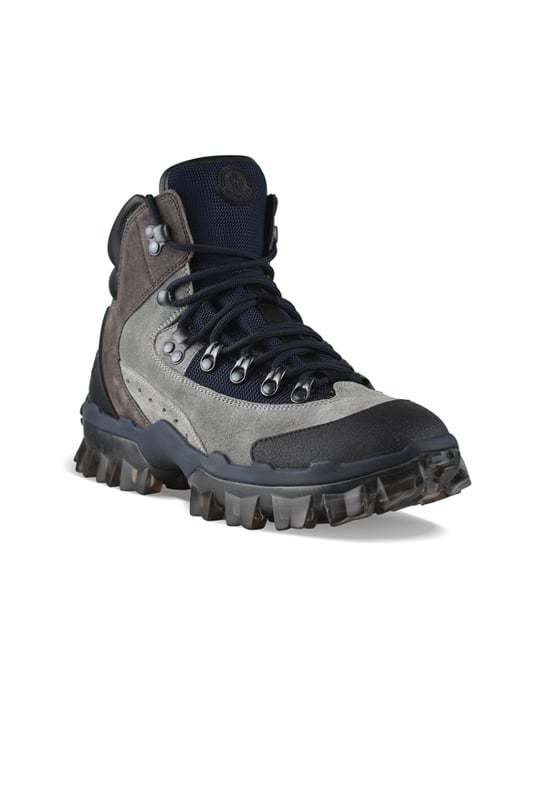 Herlot-laarzen van Moncler bruin en grijs suède.Zwart lederen schouderstuk.Zwarte rubberen ronde neus.Zwarte vetersluiting.Marineblauwe mesh tong.Rubberen logo op tong.Logo in reliëf op rubberen zool.Grijze transparante rubberen buitenzool.