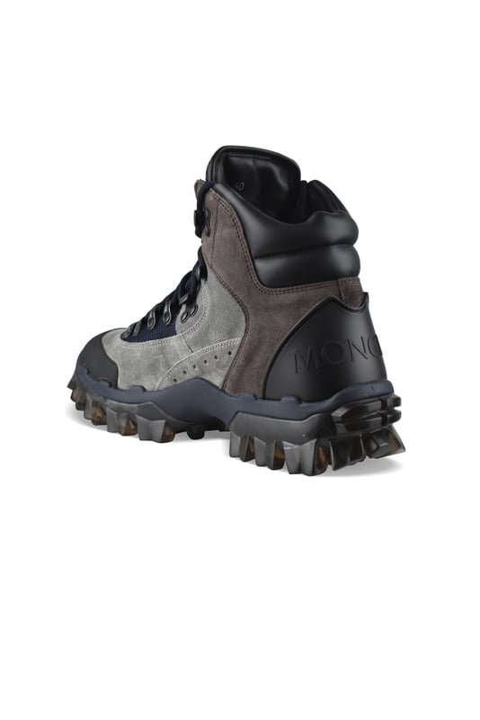 Herlot-laarzen van Moncler bruin en grijs suède.Zwart lederen schouderstuk.Zwarte rubberen ronde neus.Zwarte vetersluiting.Marineblauwe mesh tong.Rubberen logo op tong.Logo in reliëf op rubberen zool.Grijze transparante rubberen buitenzool.