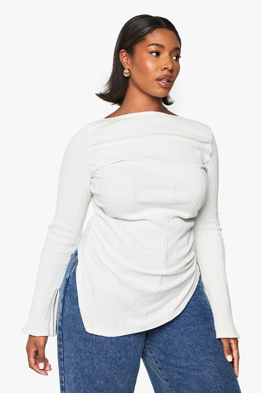 Asymmetrical design for a unique silhouette
        Ribbed texture adds depth and interest
        Wide bell sleeves for a dramatic flair
        Side ruching detail for a flattering fit
        Curved hemline with side slits for added movement
    
    Make a statement in this eye-catching plus-size top that combines comfort with contemporary style. The asymmetrical design and wide bell sleeves create a striking silhouette that's sure to turn heads. The ribbed texture adds a tactile element, while the side ruching ensures a flattering fit for all body types. Perfect for casual outings, this versatile piece can be dressed up or down with ease. Pair it with your favourite jeans and trainers for a relaxed daytime look, or team it with sleek trousers and heeled boots for an evening out. The curved hemline with side slits allows for effortless movement, making it ideal for family gatherings or casual catch-ups with friends. Embrace your individuality and showcase your fashion-forward sensibility with this must-have addition to your wardrobe.