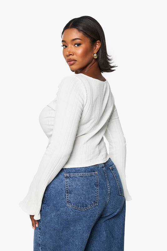 Asymmetrical design for a unique silhouette
        Ribbed texture adds depth and interest
        Wide bell sleeves for a dramatic flair
        Side ruching detail for a flattering fit
        Curved hemline with side slits for added movement
    
    Make a statement in this eye-catching plus-size top that combines comfort with contemporary style. The asymmetrical design and wide bell sleeves create a striking silhouette that's sure to turn heads. The ribbed texture adds a tactile element, while the side ruching ensures a flattering fit for all body types. Perfect for casual outings, this versatile piece can be dressed up or down with ease. Pair it with your favourite jeans and trainers for a relaxed daytime look, or team it with sleek trousers and heeled boots for an evening out. The curved hemline with side slits allows for effortless movement, making it ideal for family gatherings or casual catch-ups with friends. Embrace your individuality and showcase your fashion-forward sensibility with this must-have addition to your wardrobe.