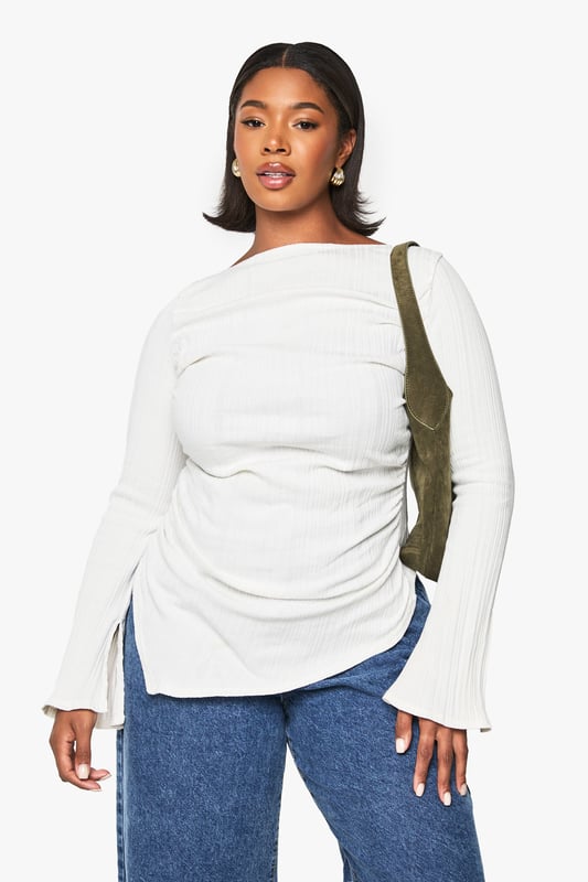 Asymmetrical design for a unique silhouette
        Ribbed texture adds depth and interest
        Wide bell sleeves for a dramatic flair
        Side ruching detail for a flattering fit
        Curved hemline with side slits for added movement
    
    Make a statement in this eye-catching plus-size top that combines comfort with contemporary style. The asymmetrical design and wide bell sleeves create a striking silhouette that's sure to turn heads. The ribbed texture adds a tactile element, while the side ruching ensures a flattering fit for all body types. Perfect for casual outings, this versatile piece can be dressed up or down with ease. Pair it with your favourite jeans and trainers for a relaxed daytime look, or team it with sleek trousers and heeled boots for an evening out. The curved hemline with side slits allows for effortless movement, making it ideal for family gatherings or casual catch-ups with friends. Embrace your individuality and showcase your fashion-forward sensibility with this must-have addition to your wardrobe.