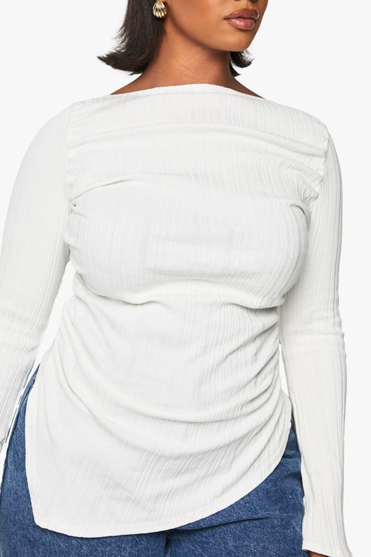 Asymmetrical design for a unique silhouette
        Ribbed texture adds depth and interest
        Wide bell sleeves for a dramatic flair
        Side ruching detail for a flattering fit
        Curved hemline with side slits for added movement
    
    Make a statement in this eye-catching plus-size top that combines comfort with contemporary style. The asymmetrical design and wide bell sleeves create a striking silhouette that's sure to turn heads. The ribbed texture adds a tactile element, while the side ruching ensures a flattering fit for all body types. Perfect for casual outings, this versatile piece can be dressed up or down with ease. Pair it with your favourite jeans and trainers for a relaxed daytime look, or team it with sleek trousers and heeled boots for an evening out. The curved hemline with side slits allows for effortless movement, making it ideal for family gatherings or casual catch-ups with friends. Embrace your individuality and showcase your fashion-forward sensibility with this must-have addition to your wardrobe.