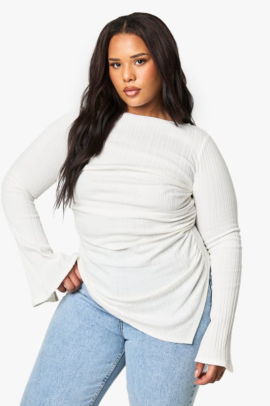 Asymmetrical design for a unique silhouette
        Ribbed texture adds depth and interest
        Wide bell sleeves for a dramatic flair
        Side ruching detail for a flattering fit
        Curved hemline with side slits for added movement
    
    Make a statement in this eye-catching plus-size top that combines comfort with contemporary style. The asymmetrical design and wide bell sleeves create a striking silhouette that's sure to turn heads. The ribbed texture adds a tactile element, while the side ruching ensures a flattering fit for all body types. Perfect for casual outings, this versatile piece can be dressed up or down with ease. Pair it with your favourite jeans and trainers for a relaxed daytime look, or team it with sleek trousers and heeled boots for an evening out. The curved hemline with side slits allows for effortless movement, making it ideal for family gatherings or casual catch-ups with friends. Embrace your individuality and showcase your fashion-forward sensibility with this must-have addition to your wardrobe.