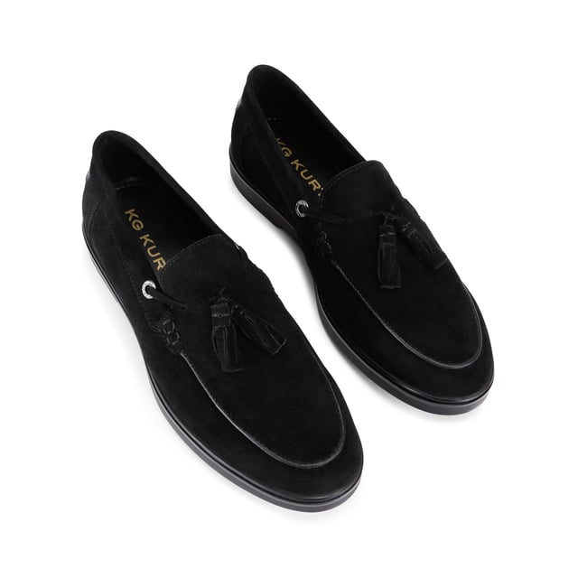 The KG Kurt Geiger Ronan is a slip-on shoe crafted from a black suede leather. There are antiqued brass branded eyelets on each side with a tassel detail on the toe.