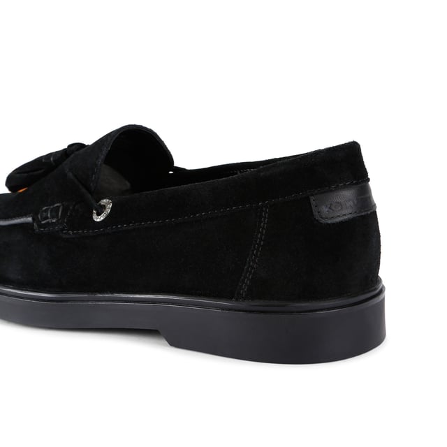 The KG Kurt Geiger Ronan is a slip-on shoe crafted from a black suede leather. There are antiqued brass branded eyelets on each side with a tassel detail on the toe.