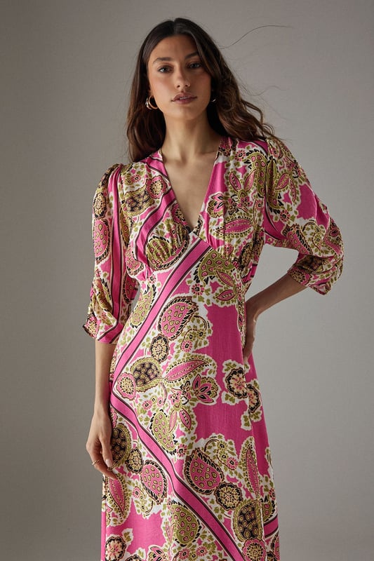 Striking paisley print midi dress with elegant V-neckline
        Feminine puff sleeves with three-quarter length for a flattering silhouette
        Flowing viscose fabric that drapes beautifully around the body
        Midi length design perfect for versatile styling options
        Subtle waist definition that enhances the feminine shape
    
    This Warehouse paisley midi dress captures confident femininity with its bold print and flattering cut. The V-neckline frames the dcolletage beautifully, while the puff sleeves add a touch of romantic charm to this contemporary piece. Style with western boots for an edgy daytime look as shown, or switch to flat sandals for relaxed weekend brunches. The flowing viscose fabric moves gracefully with every step, making it ideal for family gatherings or casual social events. For cooler days, layer with a cropped denim jacket and add statement earrings to complement the distinctive pattern. This versatile dress transitions effortlessly from day to evening - simply swap your casual footwear for block heels and add a clutch bag for dinner dates. The midi length offers the perfect balance of comfort and style for the modern British woman.