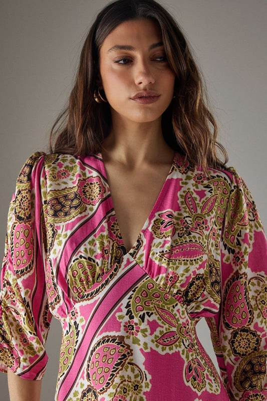 Striking paisley print midi dress with elegant V-neckline
        Feminine puff sleeves with three-quarter length for a flattering silhouette
        Flowing viscose fabric that drapes beautifully around the body
        Midi length design perfect for versatile styling options
        Subtle waist definition that enhances the feminine shape
    
    This Warehouse paisley midi dress captures confident femininity with its bold print and flattering cut. The V-neckline frames the dcolletage beautifully, while the puff sleeves add a touch of romantic charm to this contemporary piece. Style with western boots for an edgy daytime look as shown, or switch to flat sandals for relaxed weekend brunches. The flowing viscose fabric moves gracefully with every step, making it ideal for family gatherings or casual social events. For cooler days, layer with a cropped denim jacket and add statement earrings to complement the distinctive pattern. This versatile dress transitions effortlessly from day to evening - simply swap your casual footwear for block heels and add a clutch bag for dinner dates. The midi length offers the perfect balance of comfort and style for the modern British woman.
